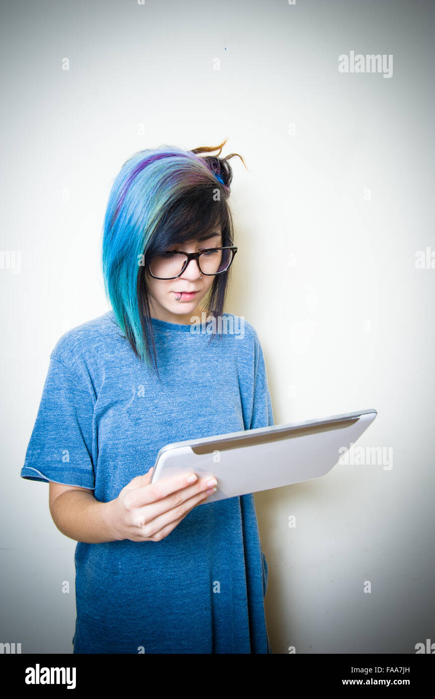 Pretty young teen woman looking and using white tablet Stock Photo
