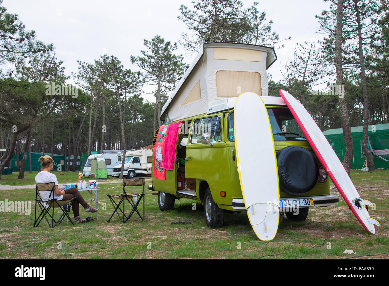 girl sit aside vw camper with surfboards at camping in portugal Stock Photo