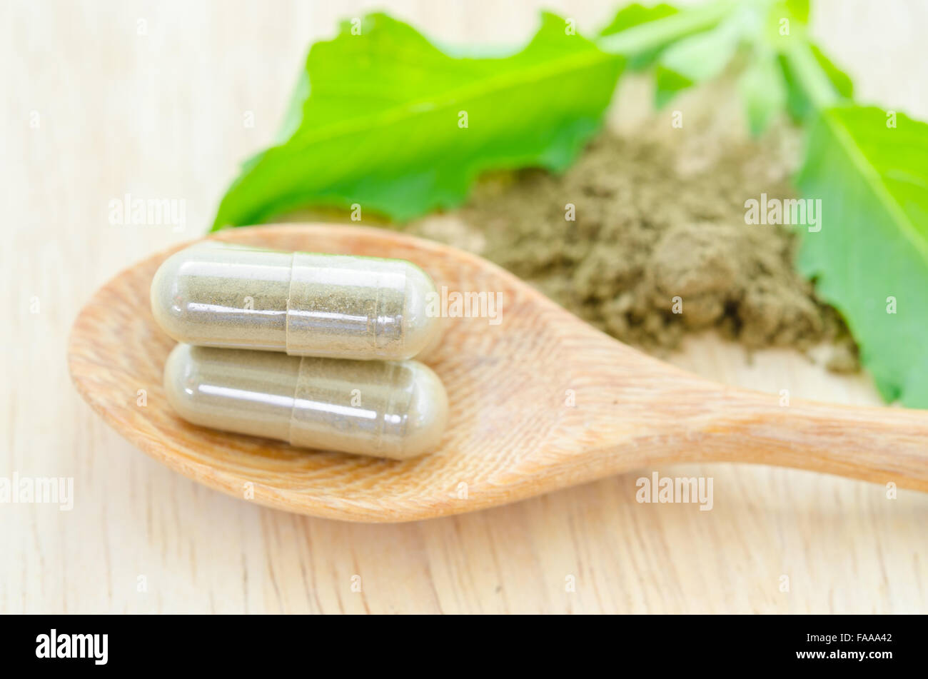 Herb capsule with green herbal leaf on wooden background. Stock Photo