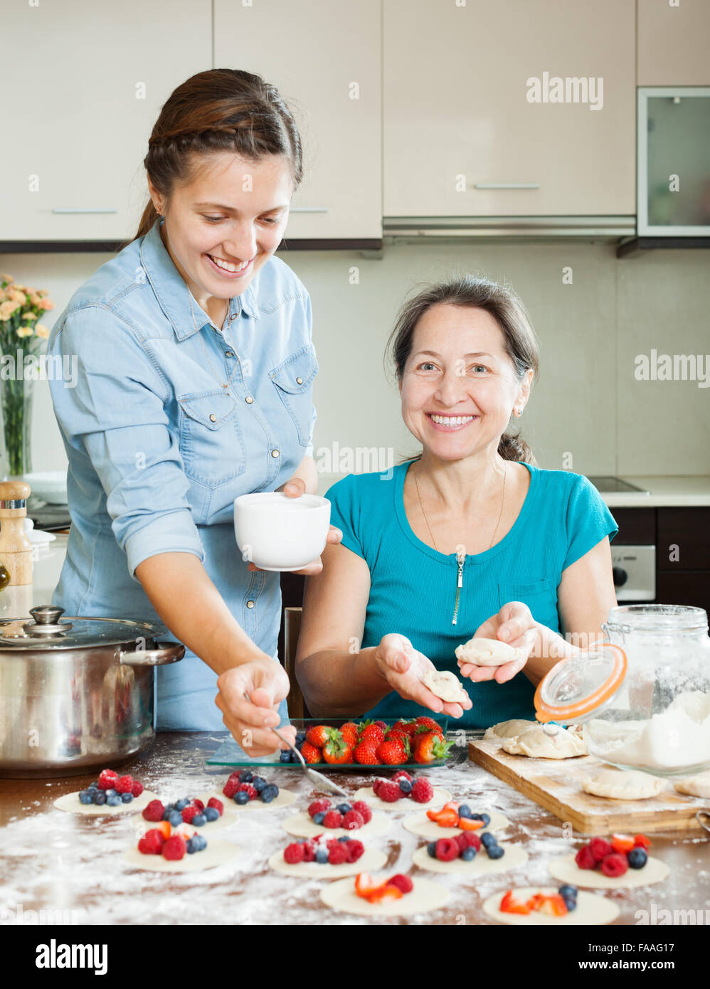 Adult daughter with mature  mother making perogies with berries Stock Photo