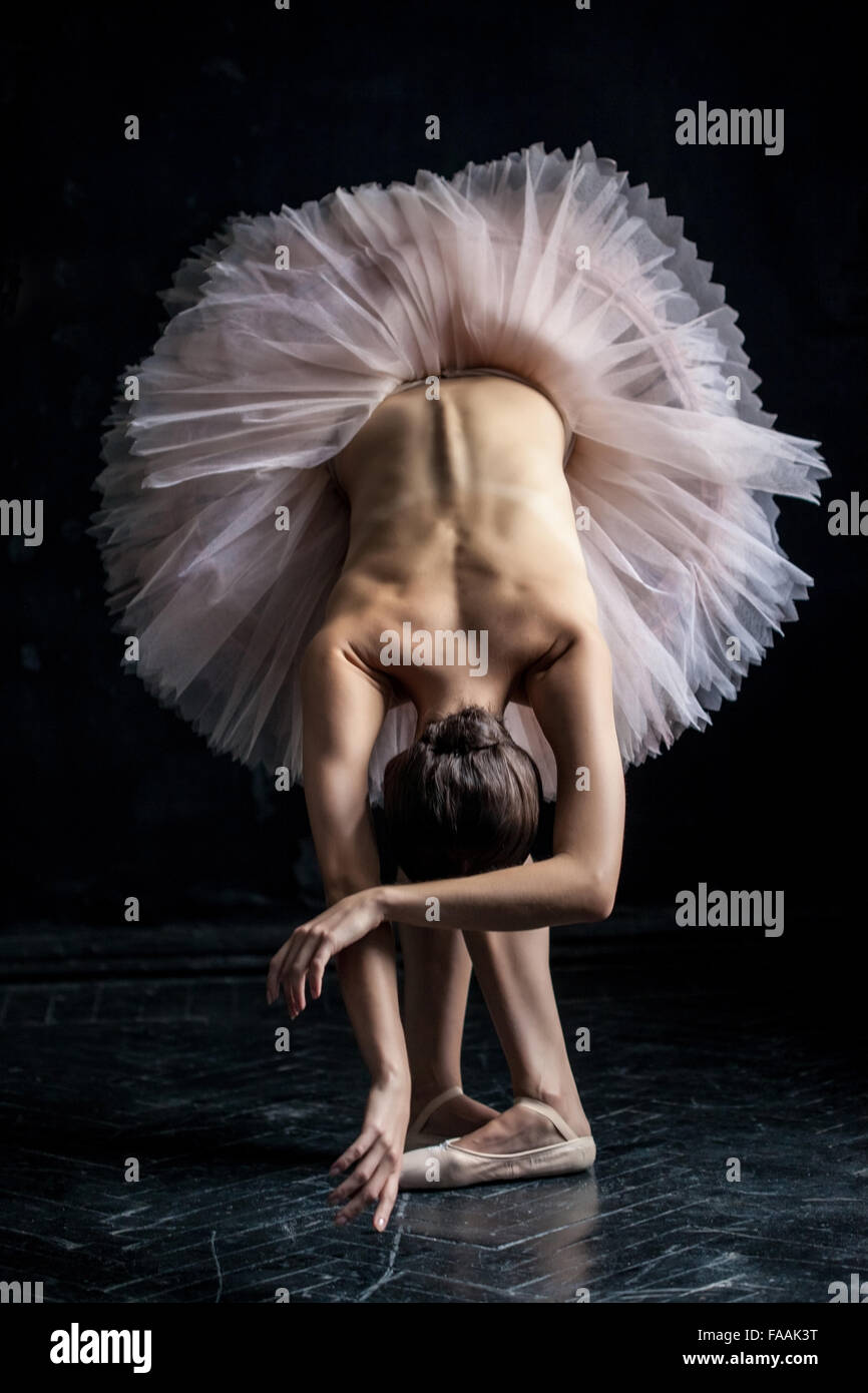 Beautiful ballerina  posing leaning on dack background Stock Photo