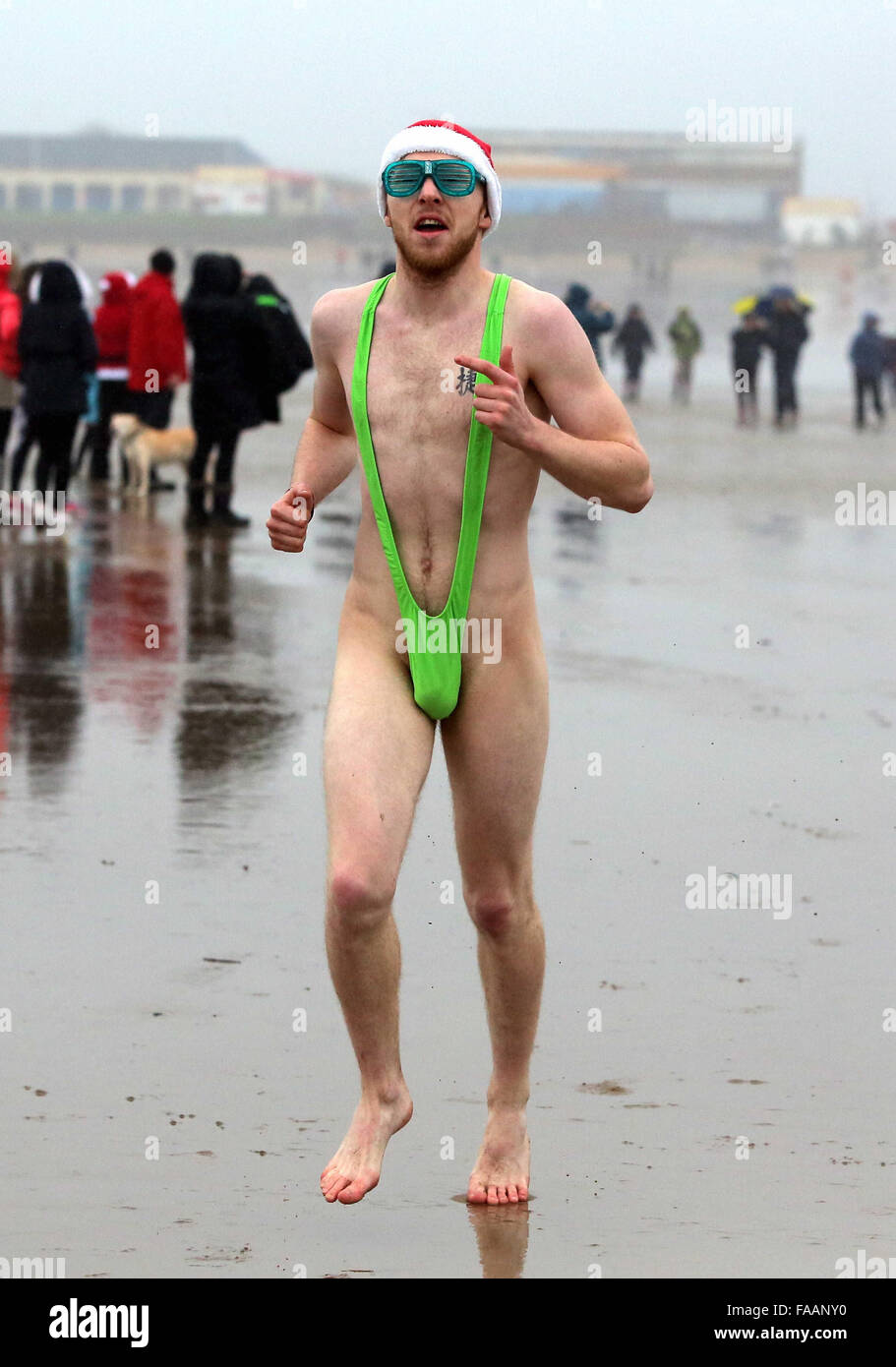 Porthcawl, UK. Friday 25 December 2015 A young man in a mankini runs towards the seaRe: Hundreds of people in fancy dress, have taken part in this year's Christmas Swim in Porthcawl, south Wales. Credit:  D Legakis/Alamy Live News Stock Photo