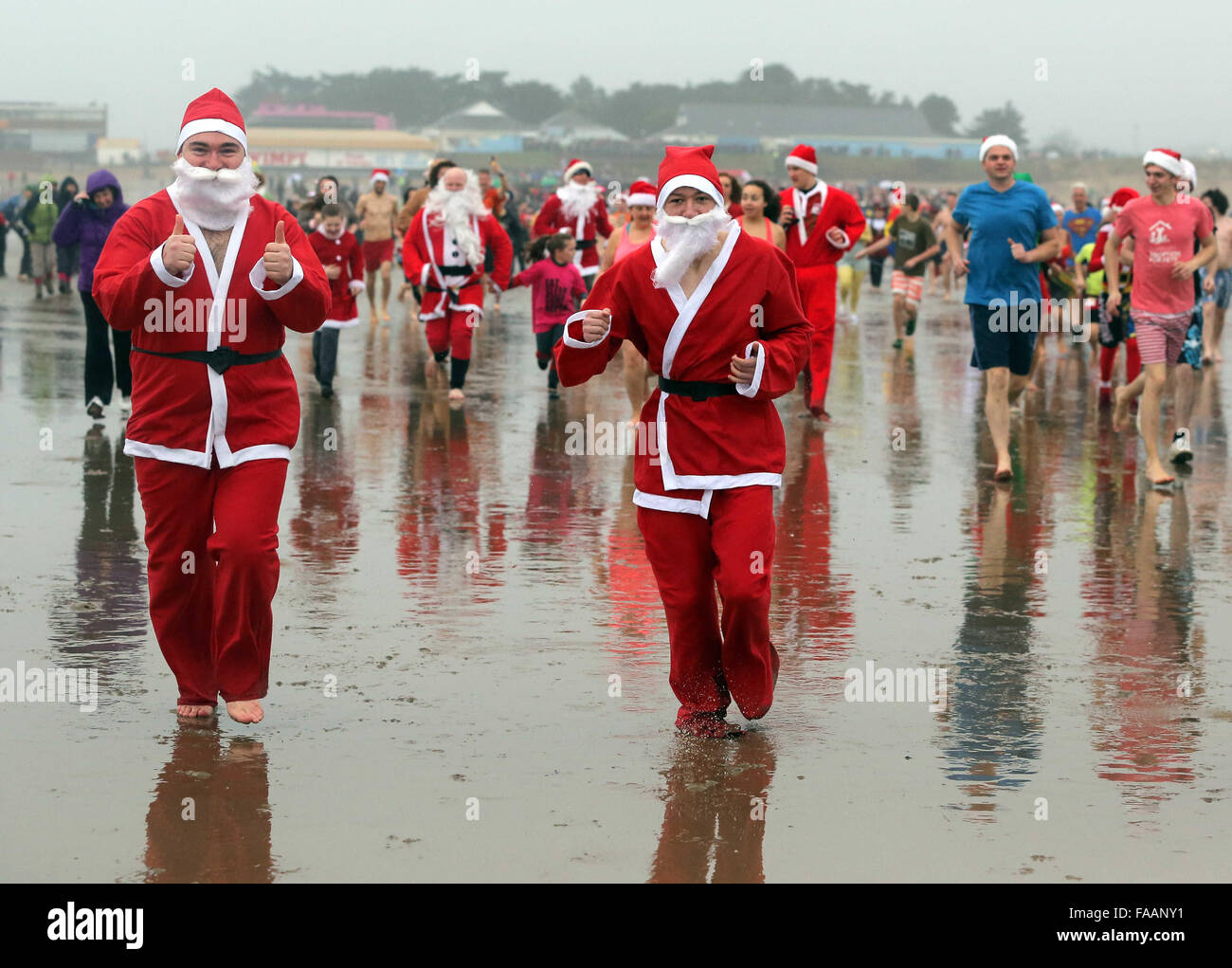 Porthcawl, UK. Friday 25 December 2015 Two Christmas swimmers in Santa costumes run towards  the seaRe: Hundreds of people in fancy dress, have taken part in this year's Christmas Swim in Porthcawl, south Wales. Credit:  D Legakis/Alamy Live News Stock Photo