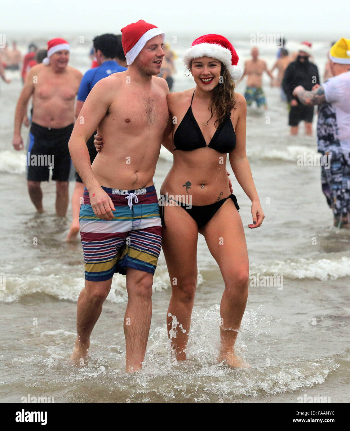 Porthcawl, UK. Friday 25 December 2015 A young couple in Santa hatsRe: Hundreds of people in fancy dress, have taken part in this year's Christmas Swim in Porthcawl, south Wales. Credit:  D Legakis/Alamy Live News Stock Photo