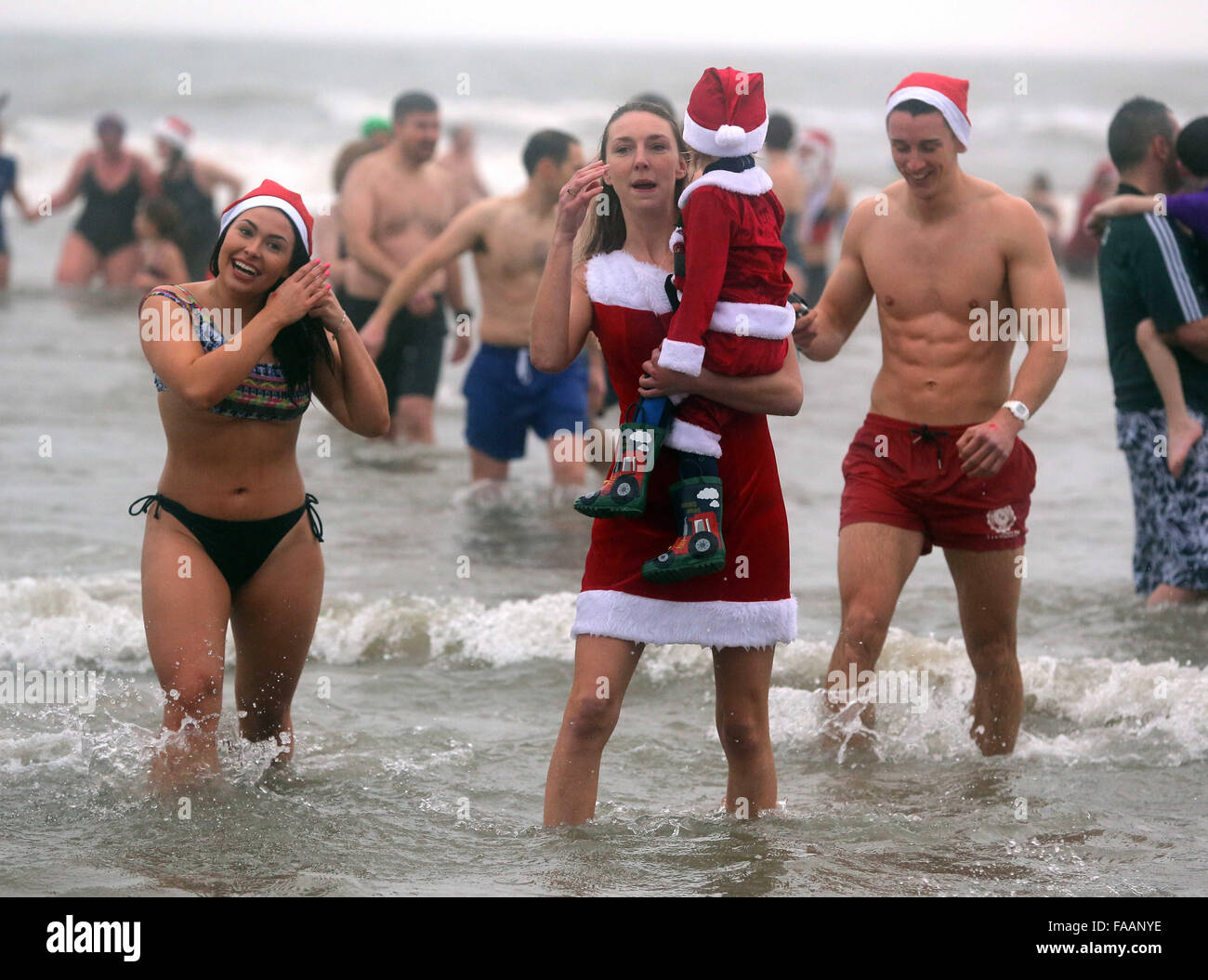 Porthcawl, UK. Friday 25 December 2015 A woman in a Santa costume is joined by her young sonRe: Hundreds of people in fancy dress, have taken part in this year's Christmas Swim in Porthcawl, south Wales. Credit:  D Legakis/Alamy Live News Stock Photo