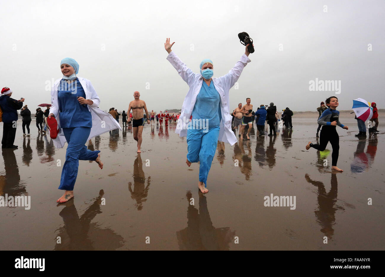 Porthcawl, UK. Friday 25 December 2015 Christmas swimmers in surgeon fancy dress run towards the seaRe: Hundreds of people in fancy dress, have taken part in this year's Christmas Swim in Porthcawl, south Wales. Credit:  D Legakis/Alamy Live News Stock Photo