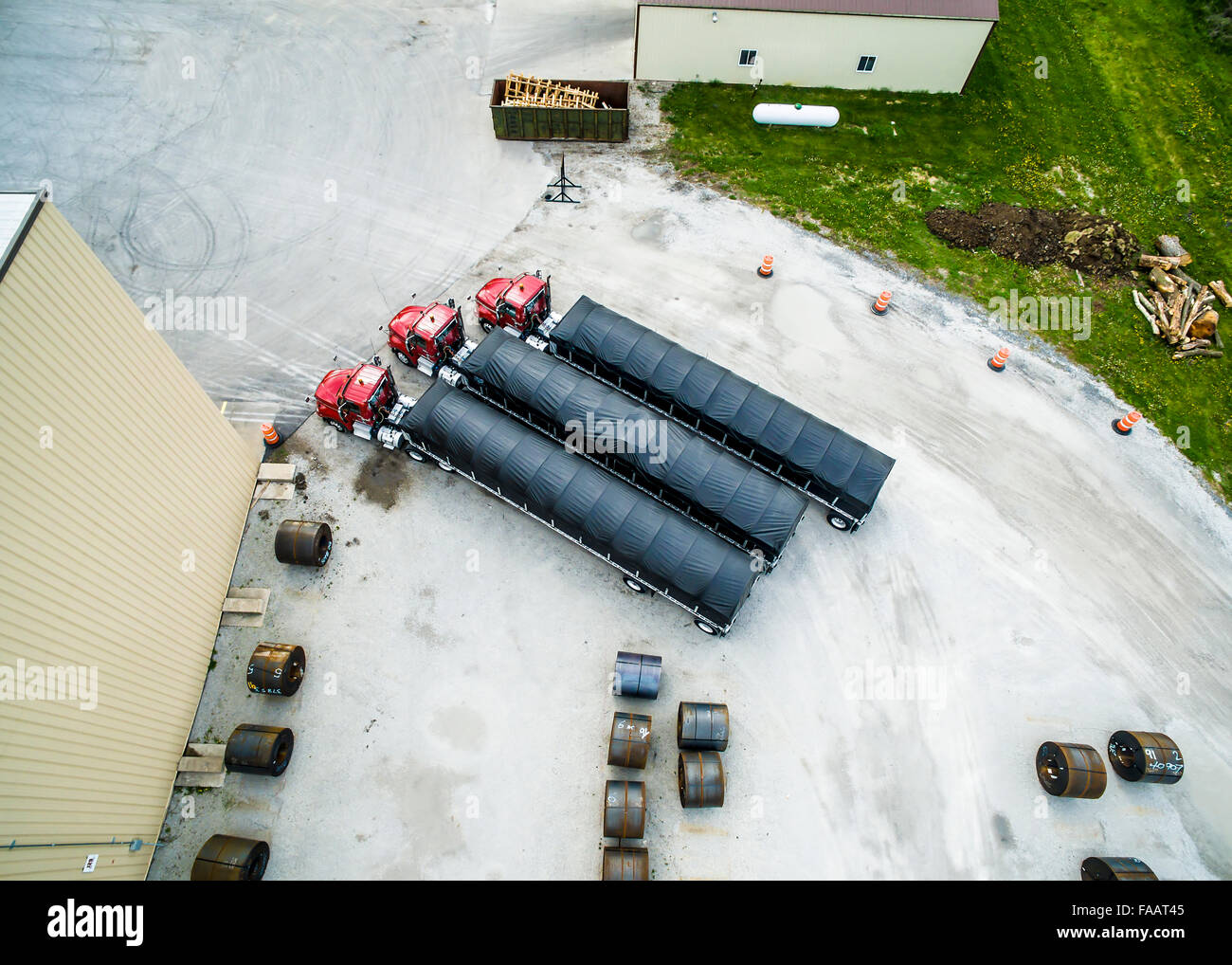 Aerial view from drone Semi tractor trailers with tarps and frames parked in parking lot with roll formed steel coils Stock Photo