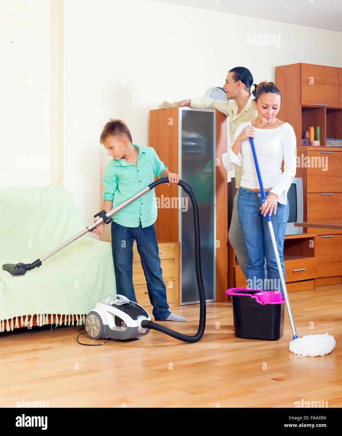 Ordinary family doing  cleaning with  cleaning equipment in living room Stock Photo