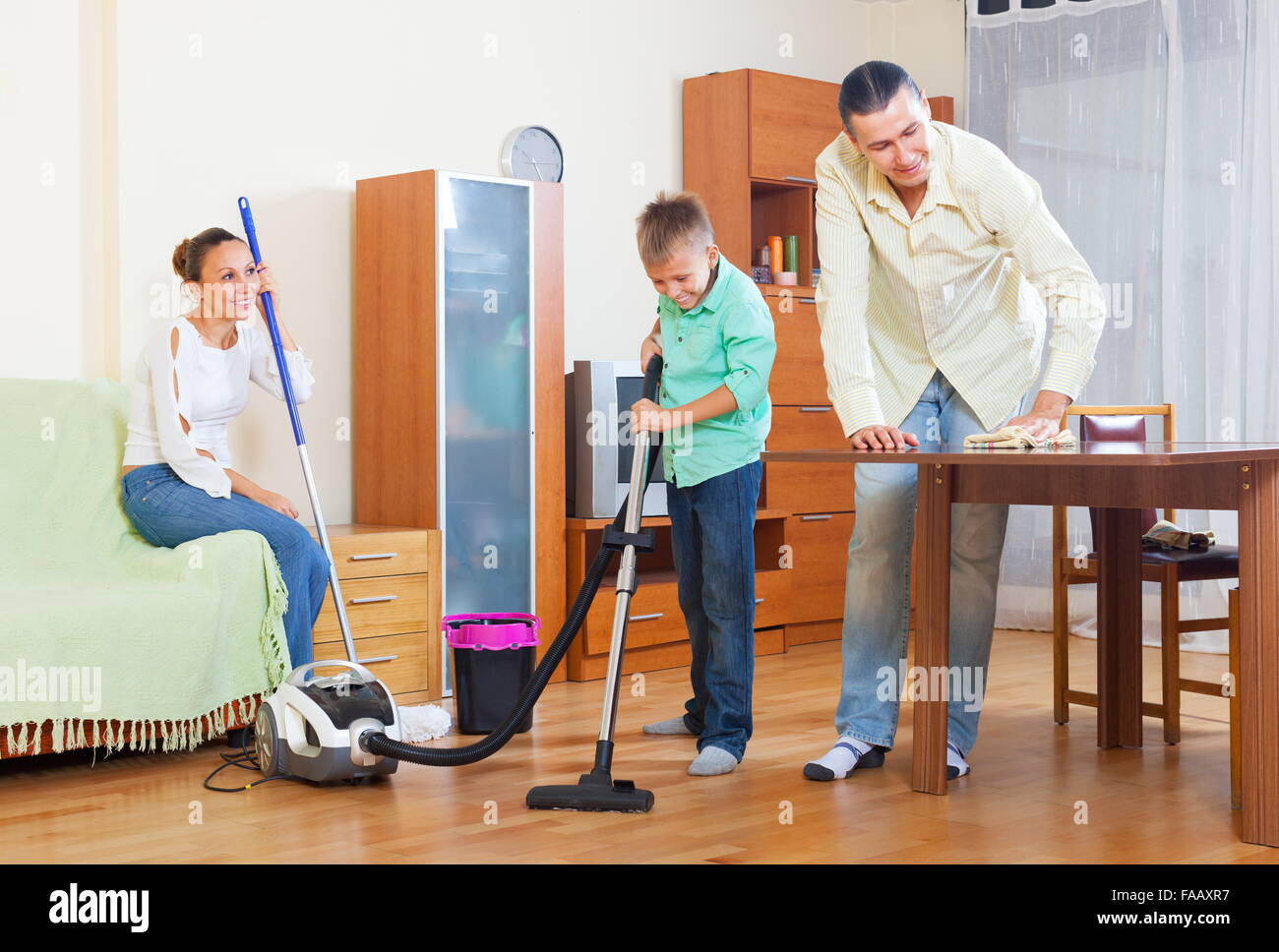 Ordinary couple and teenager boy dusting in living room Stock Photo Alamy