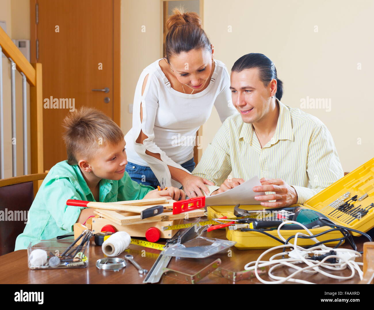 Happy family of three with teenager son doing something with the working tools Stock Photo