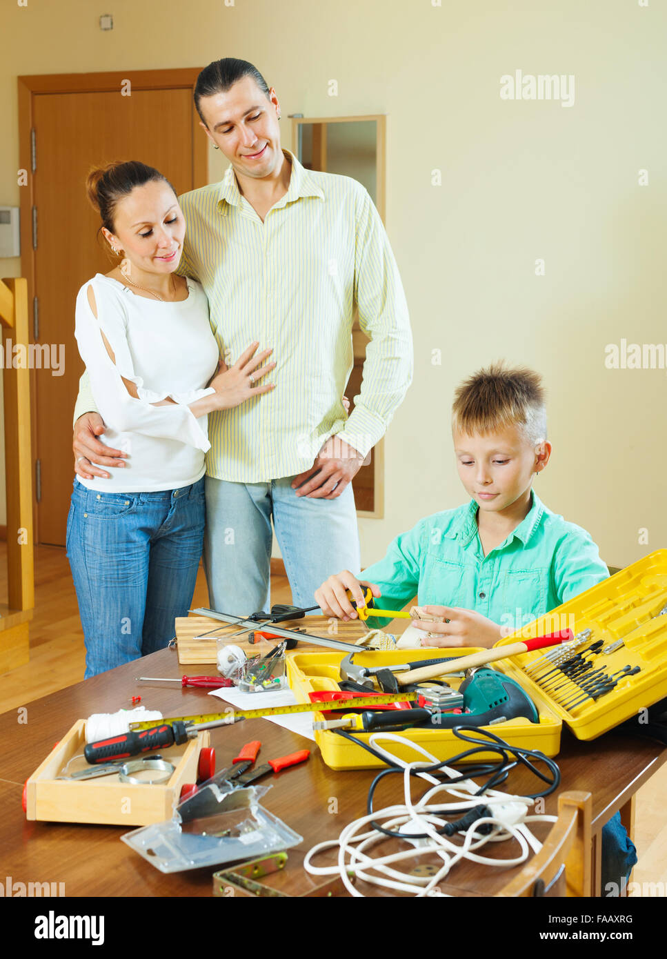 The teenager is doing something with their hands, the parents are watching Stock Photo