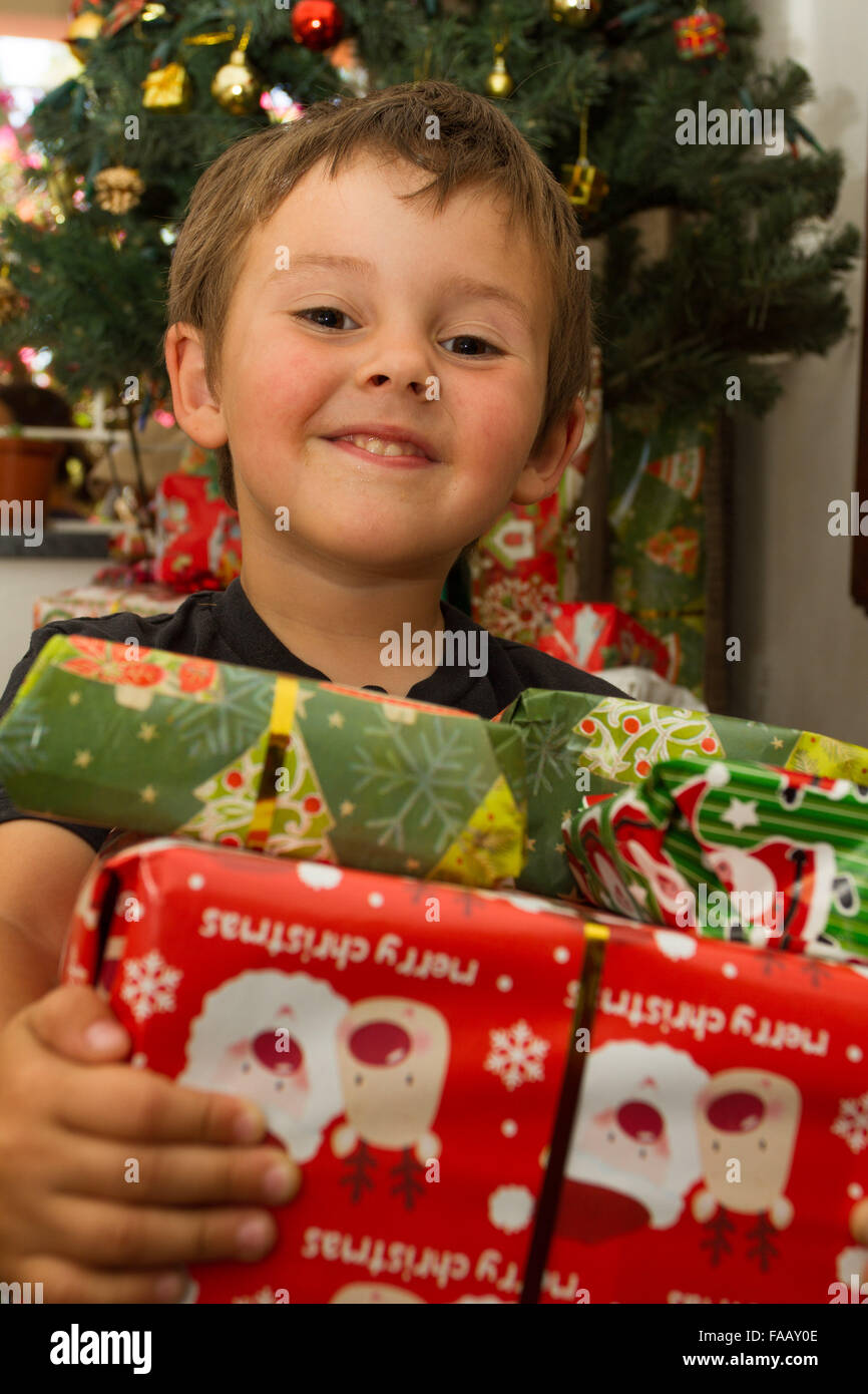 Young boy opening christmas present in front of tree. Stock Photo