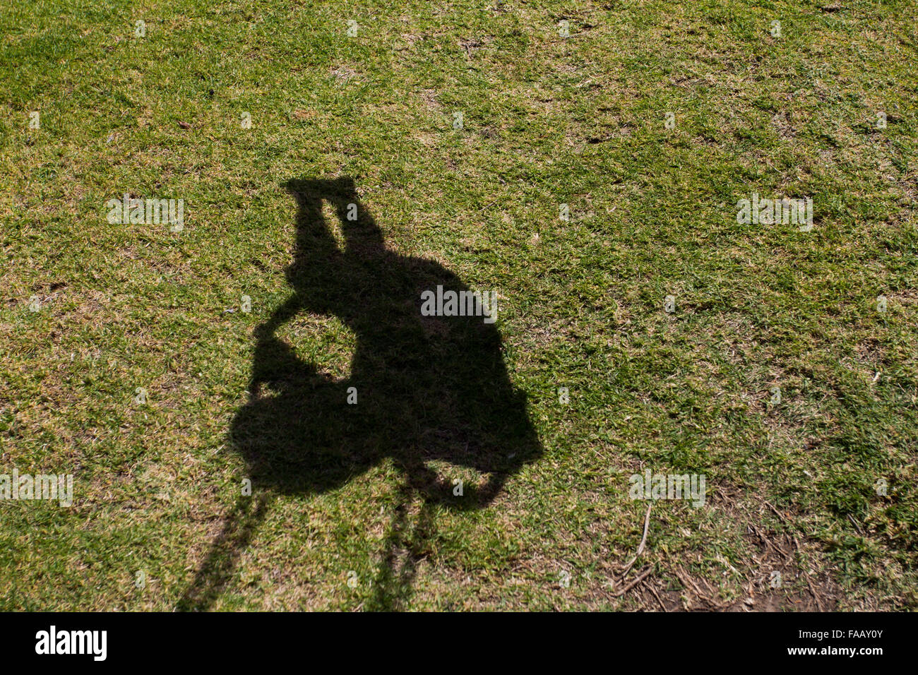 The shadow of a young boy on the swing in a play park. Stock Photo