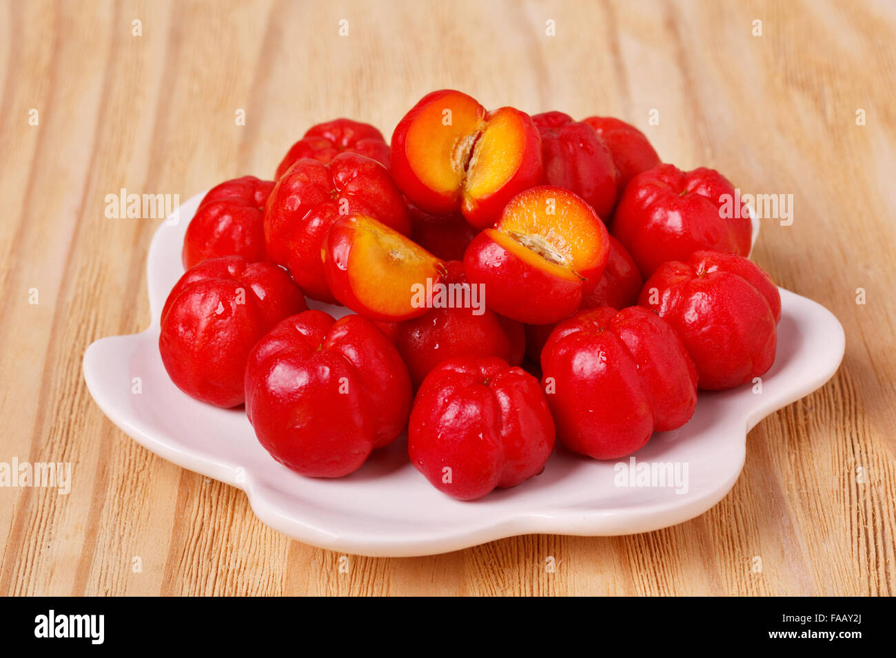 Malpighia glabra (red acerola), tropical fruit on plate on wooden table. Selective focus Stock Photo