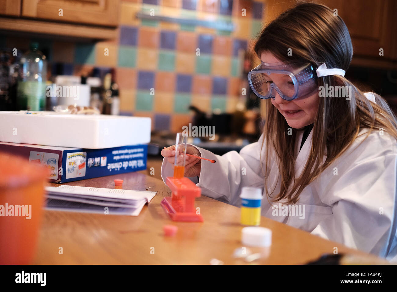 Young girl in white lab coat playing with chemistry science set Stock Photo