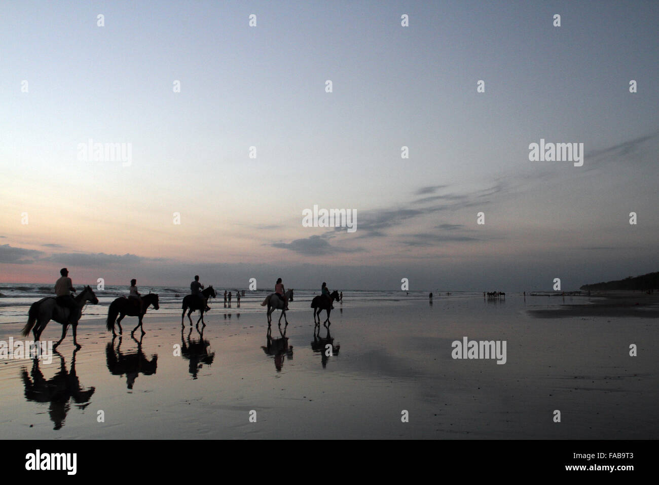 Mal Pais, Costa Rica. 25th Dec, 2015. Tourists ride horses on a beach during sunset in Mal Pais, Costa Rica, on Dec. 25, 2015. © Kent Gilbert/Xinhua/Alamy Live News Stock Photo