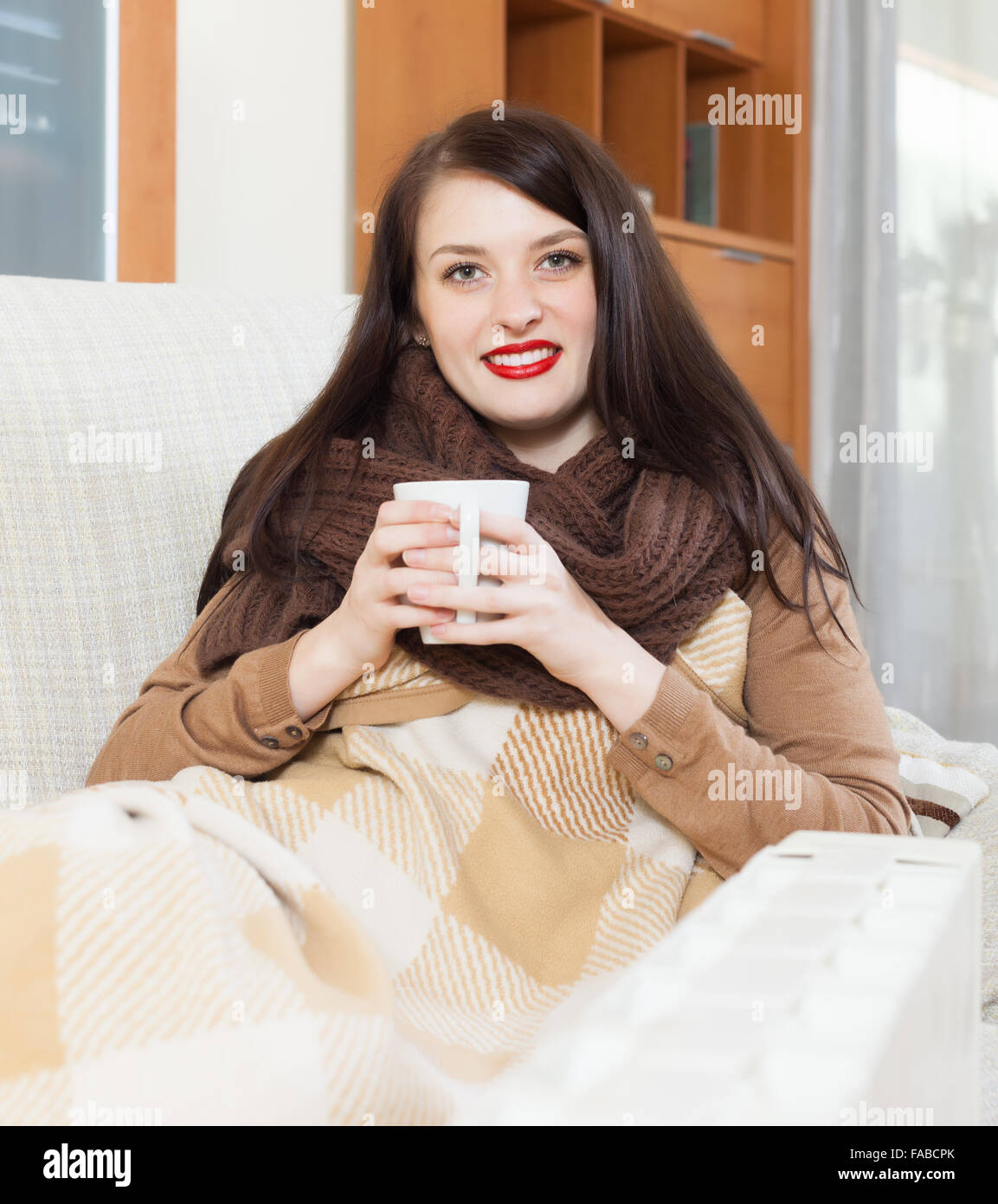 girl with cup near electric heater in home Stock Photo