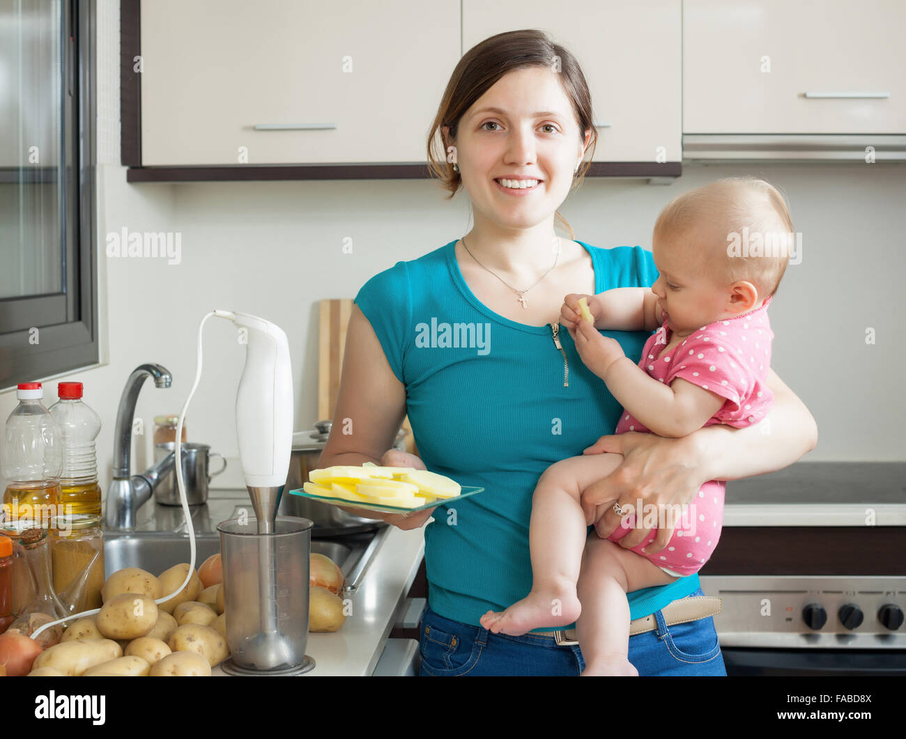 Happy woman with baby girl cooking mashed potatoes Stock Photo