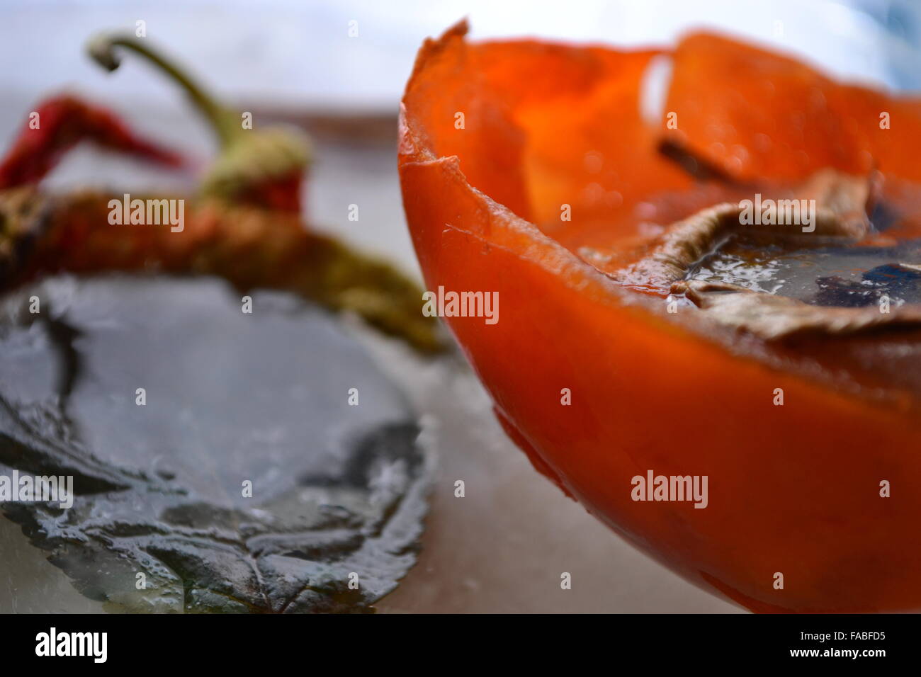 Frozen peppers persimmon leaf in melting ice Stock Photo