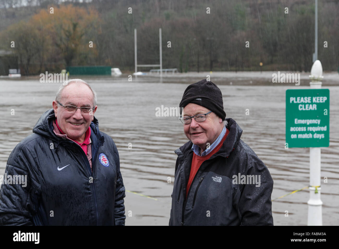 Halifax, West Yorkshire, UK. 26th December, 2015. Here, committee members Tom Walton (left) and Michael Downsborough (right) manage to keep smiling after surveying the deluge at their local rugby club. Heath RUFC in Greetland, Halifax has been flooded once again after heavy rain hits the region and causes more disruptions. Sea containers are floating around as the river Calder overflowed onto their pitch, the adjoining football pitch and the Model car racing track. Credit:  Mick Flynn/Alamy Live News Stock Photo