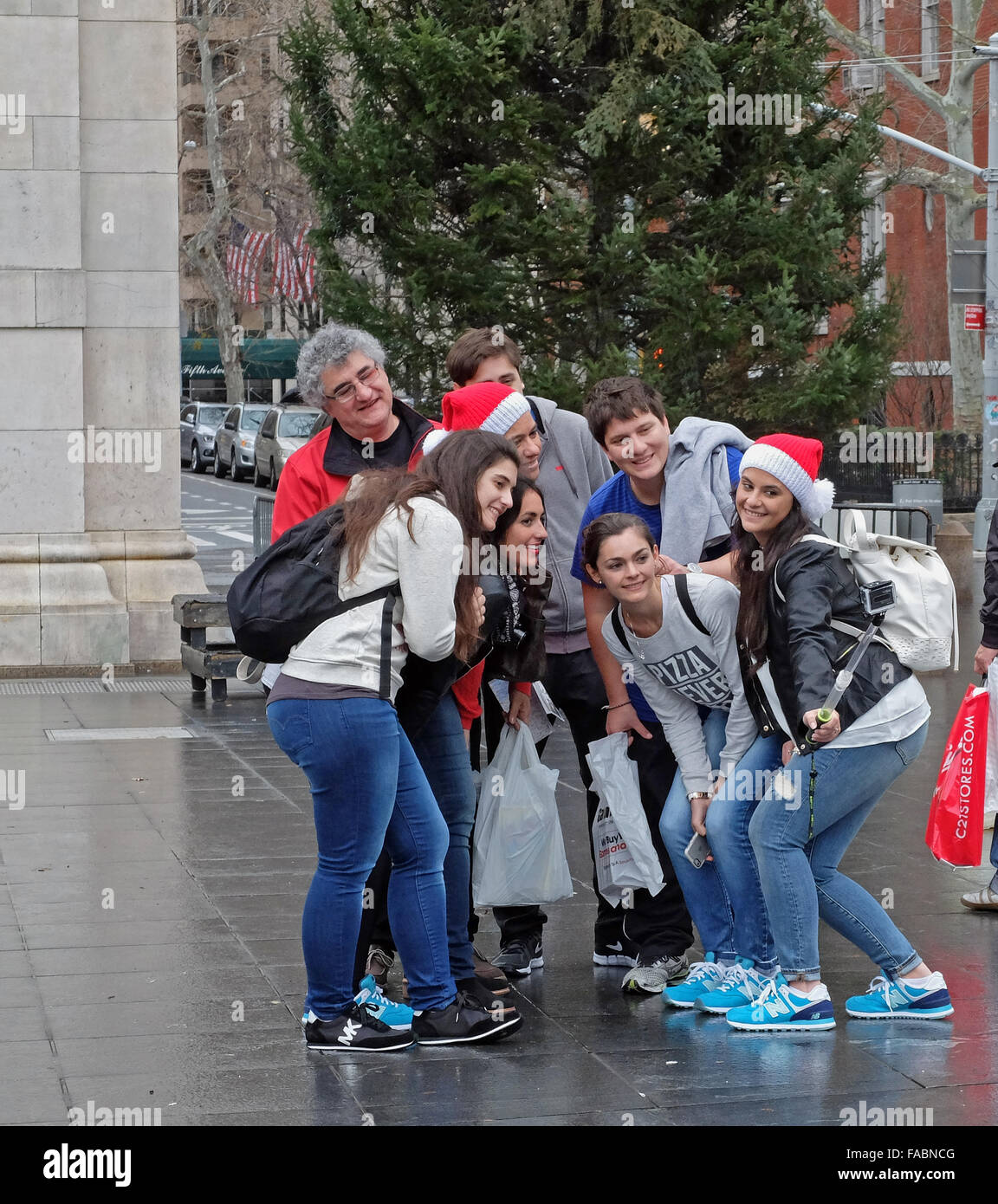 A family of tourists visiting New York pose for a selfie in front of a Christmas tree in Washington Square Park in New York City Stock Photo