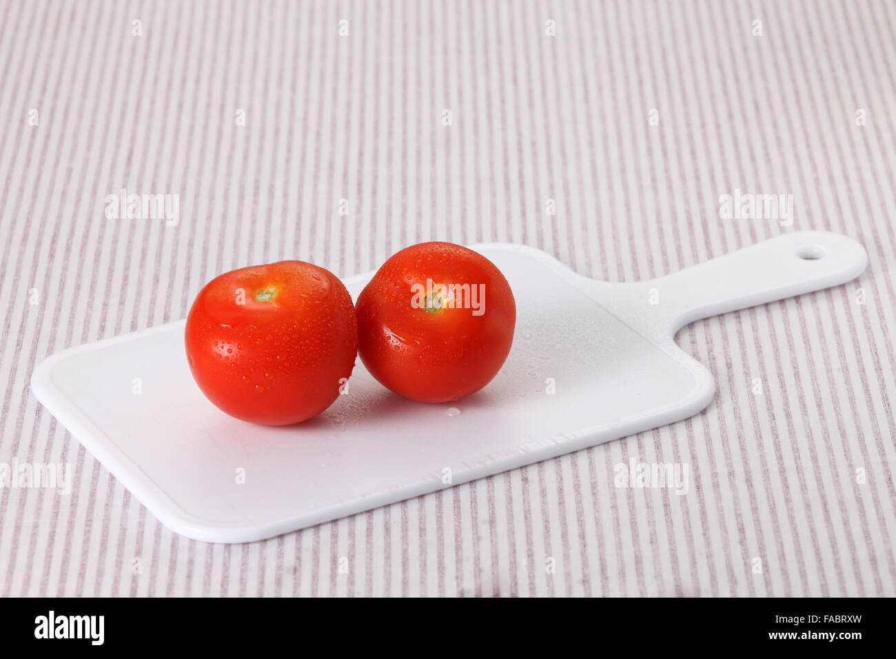 two tomatoes on the chopping board Stock Photo - Alamy
