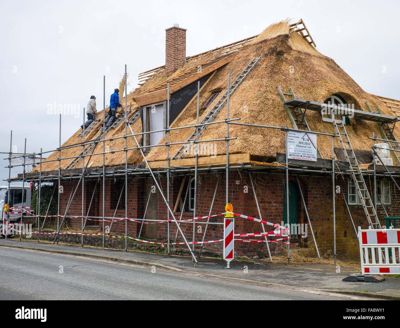 Thatchers at work restoring the thatched roof of an old farmhouse. Stock Photo