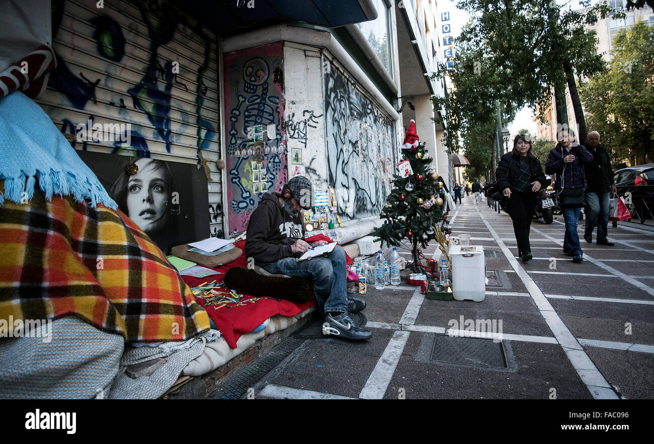A homeless man sits next to a Christmas tree in a street in Athens