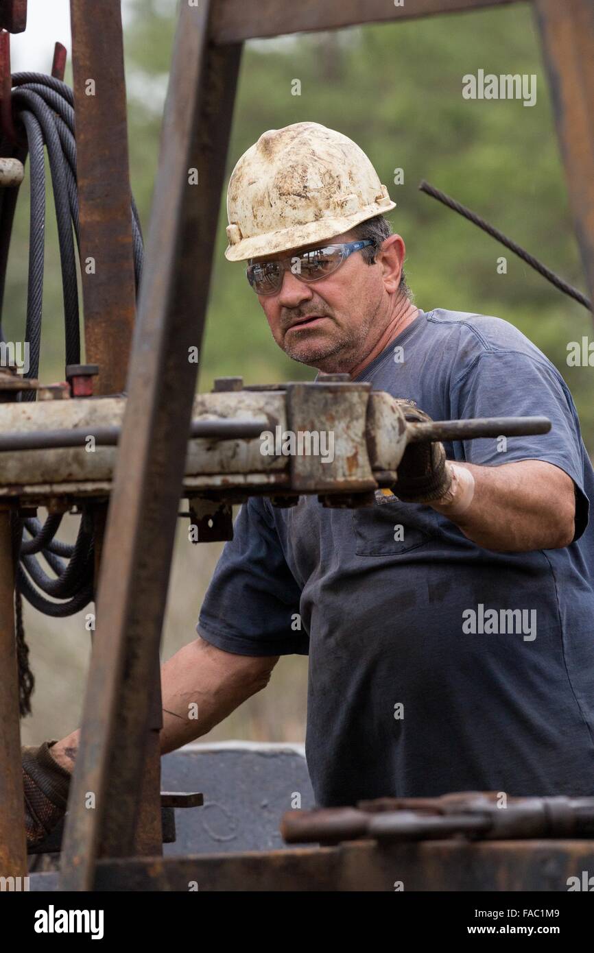 Oil workers sink pipe using a derrick to drill for crude in Evangeline, Louisiana. The oil fields were the first wells in Louisiana. Stock Photo