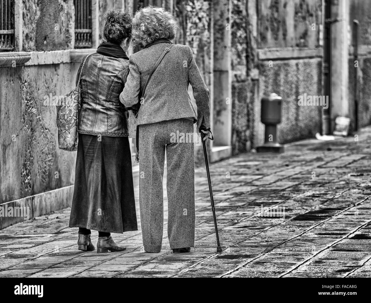 Two women walking arm in arm in Venice, Italy Stock Photo