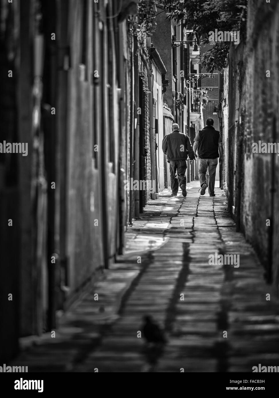 Two men walking in passegeway in Venice, Italy Stock Photo