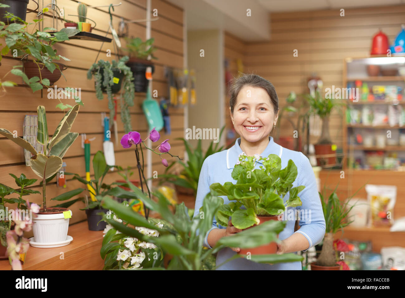 Happy mature woman in the shop surrounded by different flowers Stock Photo