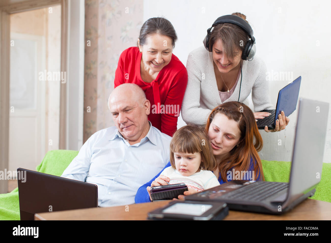 Happy multigeneration family uses various electronic devices in home ...