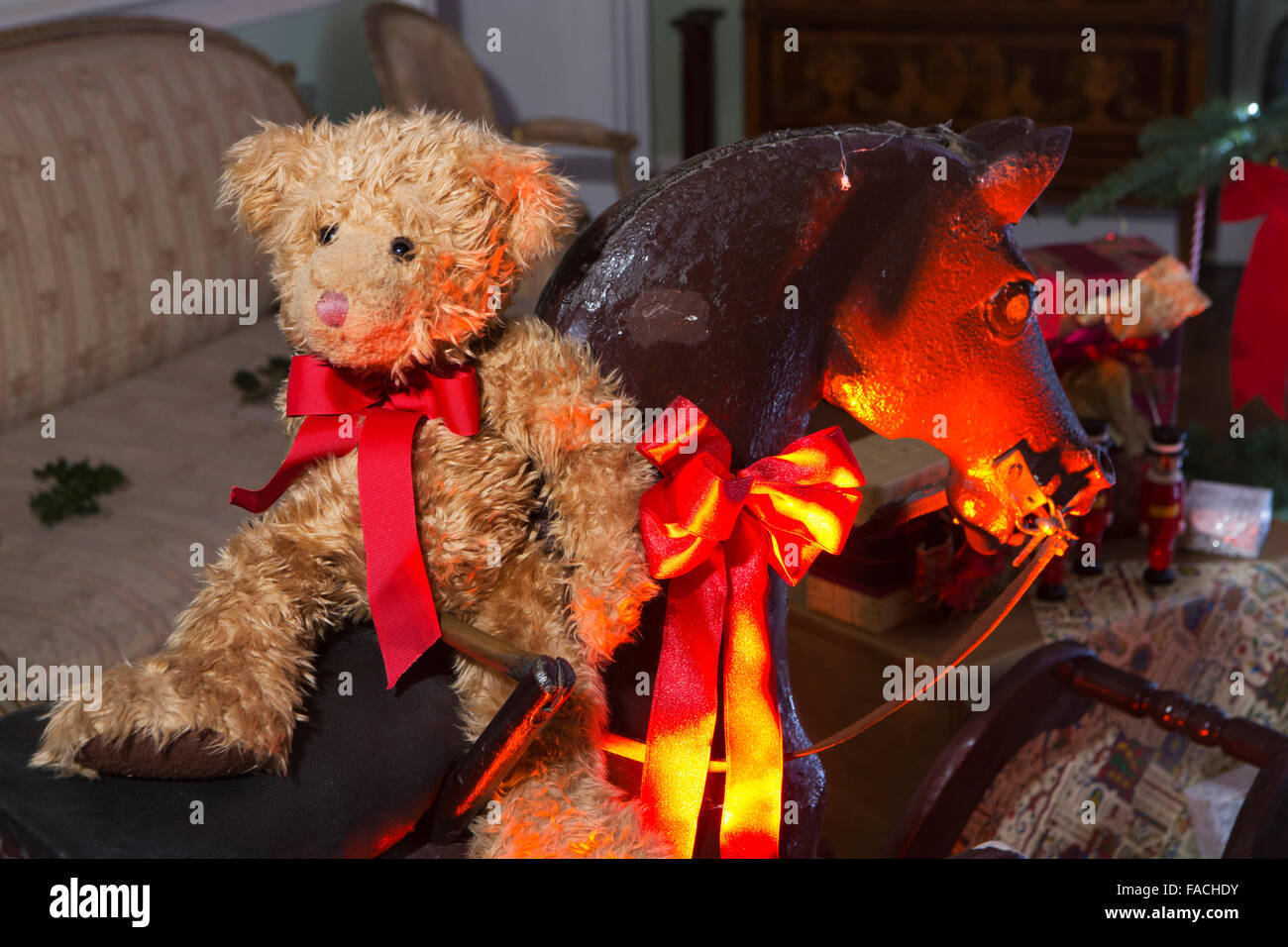 UK, England, Cheshire, Knutsford, Tatton Hall, teddy bear on rocking horse below Christmas tree Stock Photo