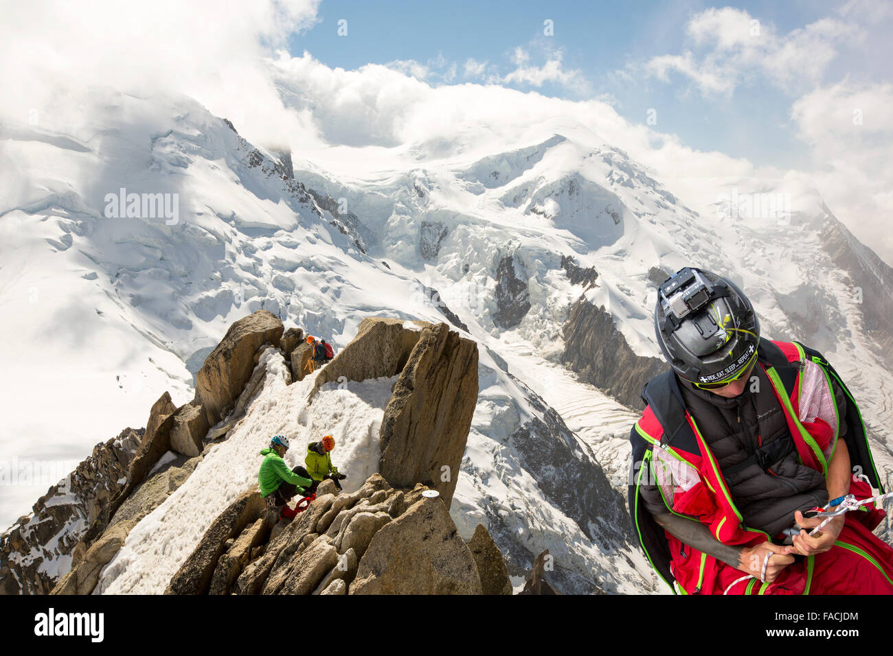 Mont Blanc from the Aiguille Du Midi above Chamonix, France, with climbers on the Cosmiques Arete and a base jumper abseiling. Stock Photo