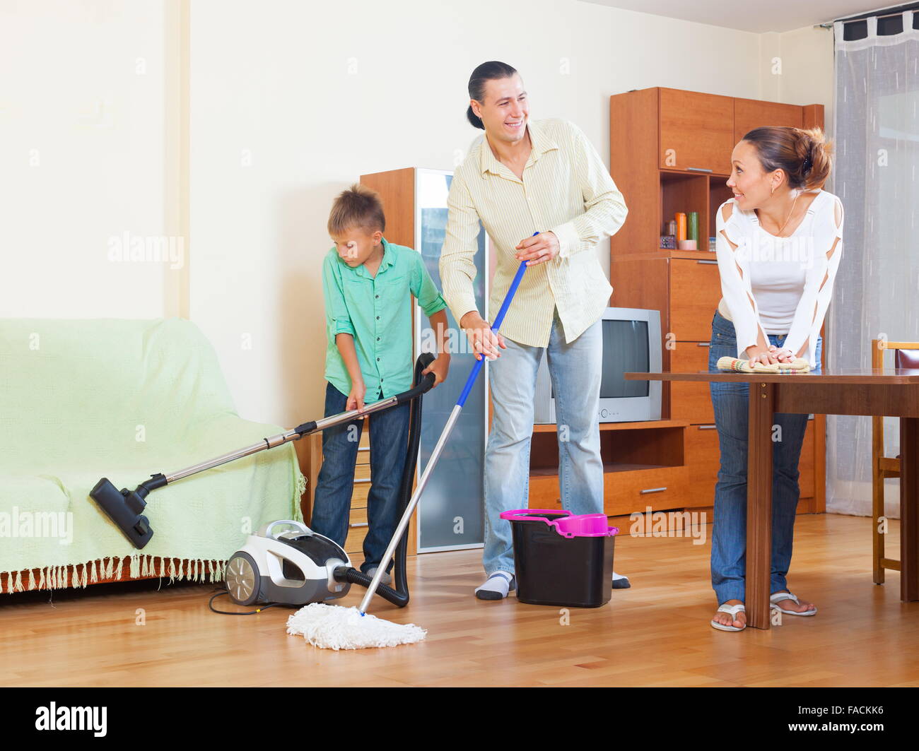 Happy family of three doing house cleaning with vacuum cleaner Stock Photo