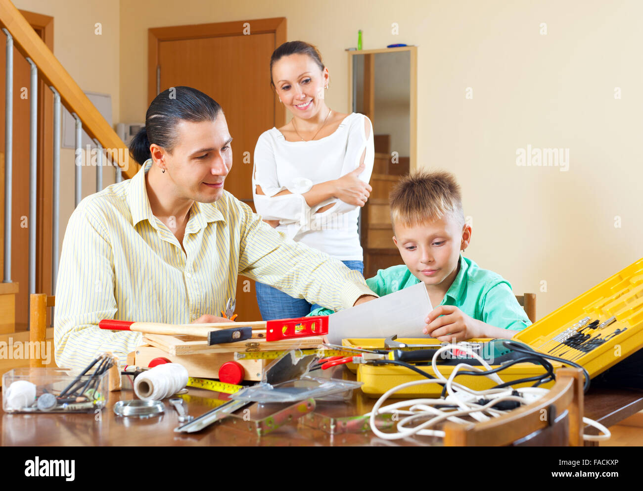 Happy family of three with teenage boy doing something with the working tools Stock Photo