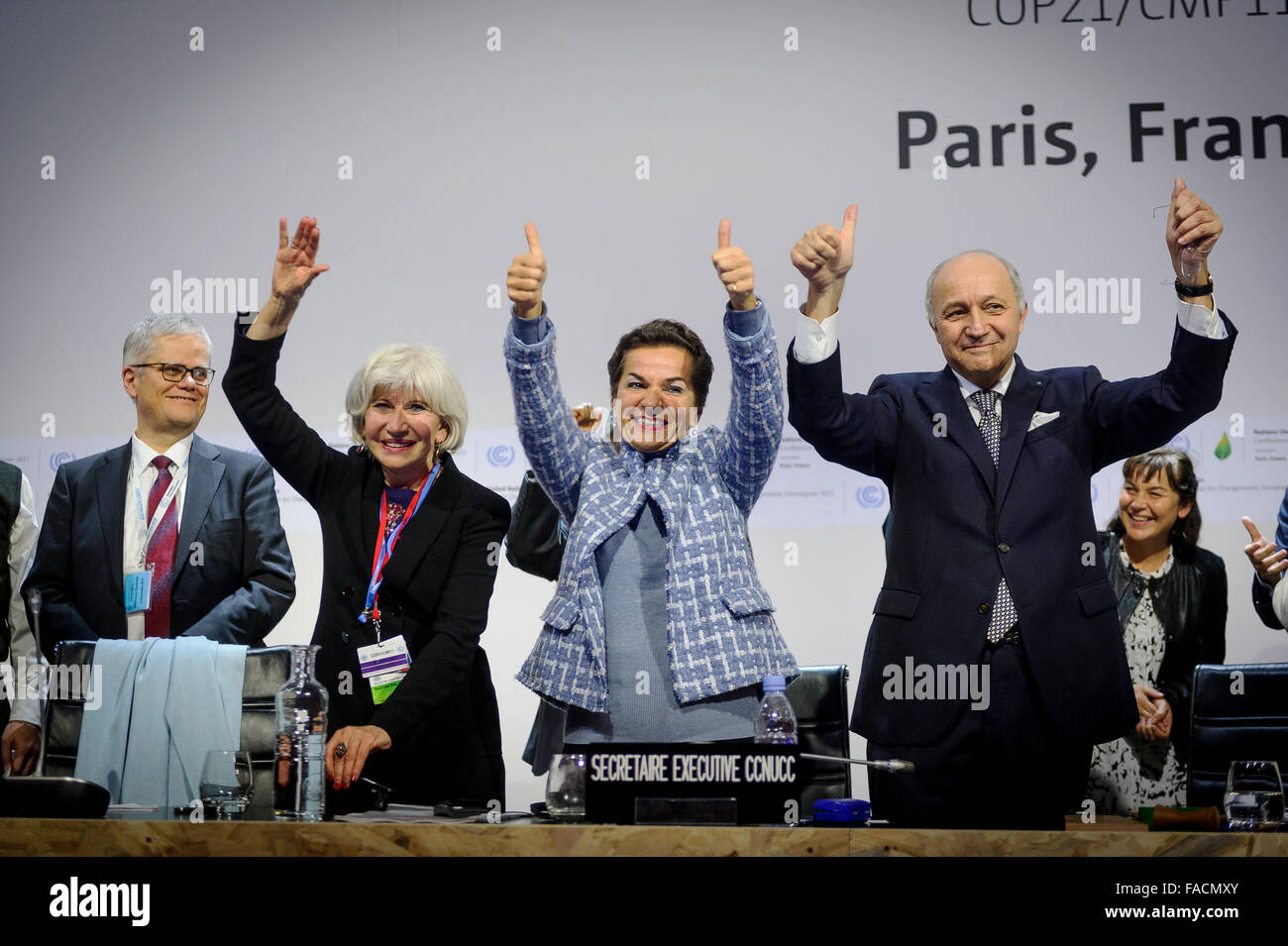 French Foreign Minister Laurent Fabius  right, joins United Nations climate chief Christiana Figuere, center, and Laurence Tubiana celebrating the agreement on climate change at the conclusion of the COP21, United Nations Climate Change Conference December 12, 2015 in Le Bourget, France. Stock Photo