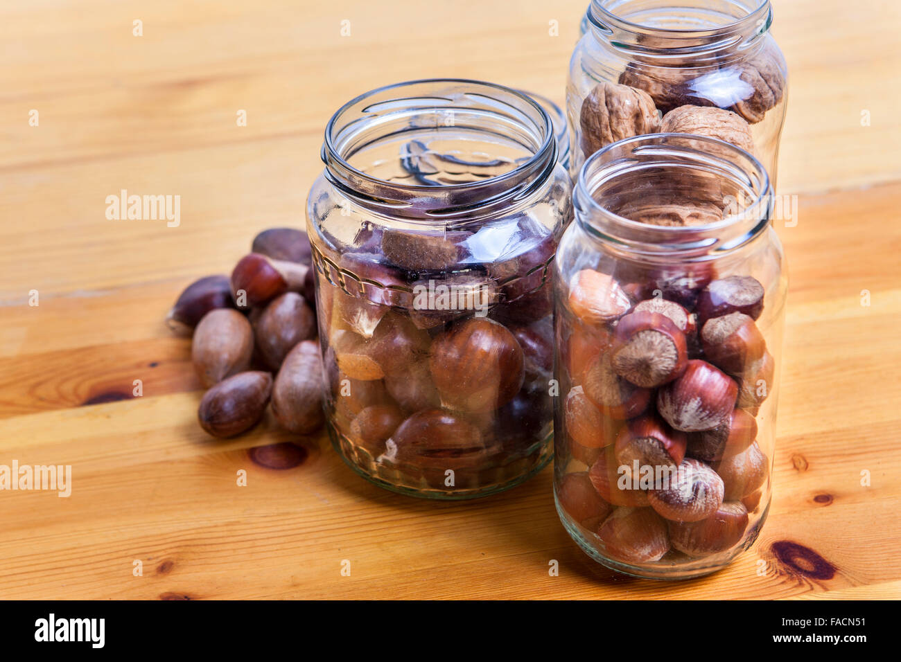 Nuts on glass jars over wooden surface. Isolated over white background Stock Photo