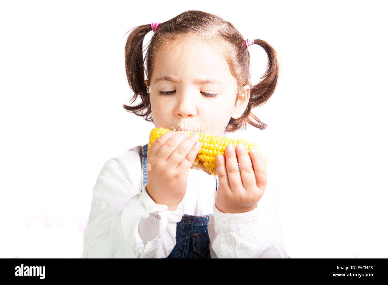 Portrait of happy girl biting a corncob. Isolated over white background Stock Photo