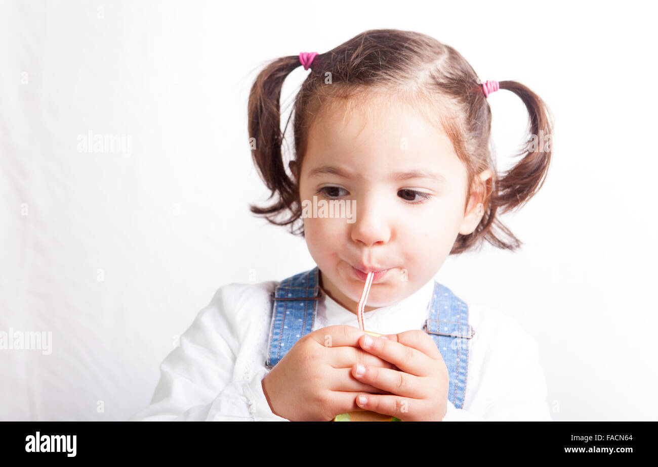 Portrait of happy girl drinking a fruit juice from a brick. Isolated over white background Stock Photo