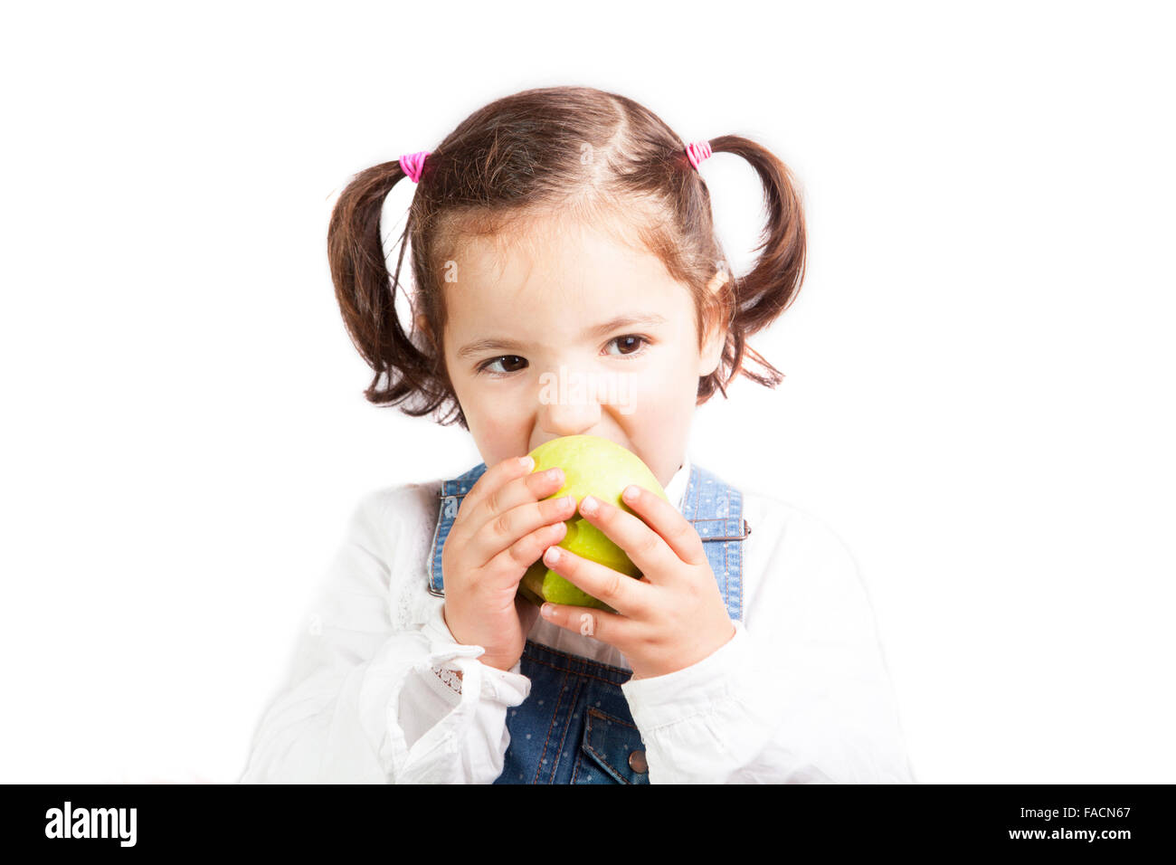 Portrait of happy girl biting a green apple. Isolated over white background Stock Photo