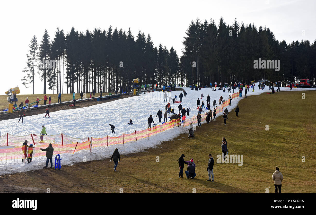 Visitors ride on the small amount of snow on the sledding hill in
