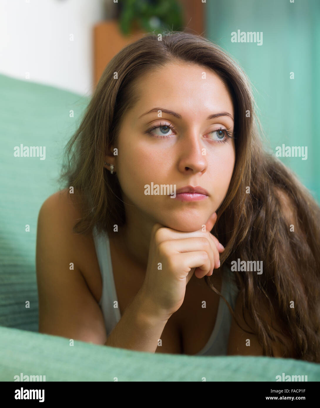 Sad young woman on sofa in home Stock Photo - Alamy
