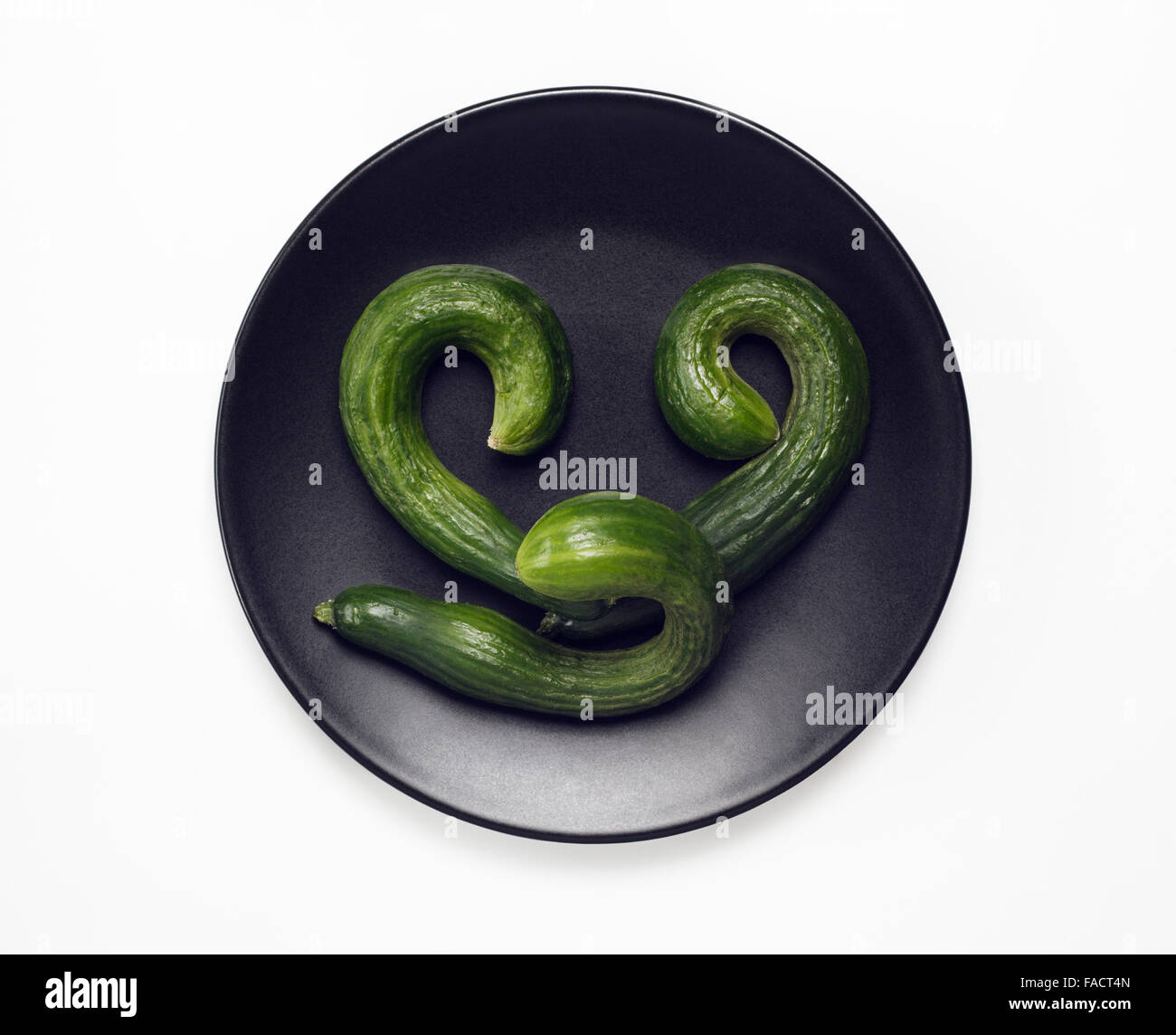 Three Courgettes on black plate Stock Photo