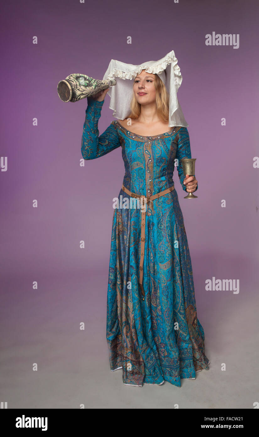 Studio shot of beautiful girl dressed as medieval lady checking a jar for liquid Stock Photo