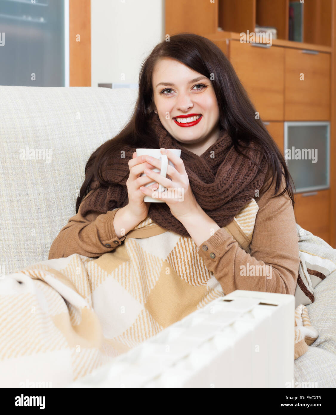 Happy woman  with cup near  electric heater in home Stock Photo