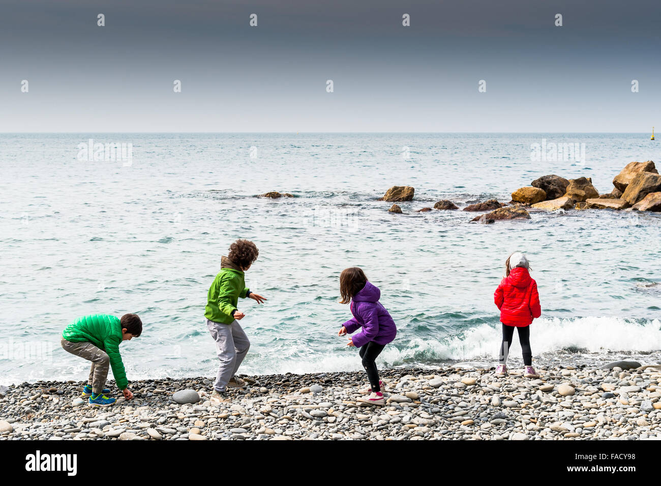 Children on holiday play by throwing stones into the sea from the beach