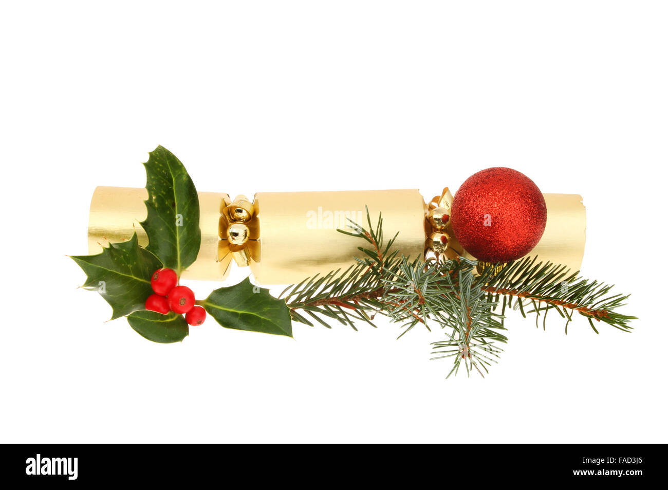 Gold foil Christmas cracker with holly pine needles and a red bauble isolated against white Stock Photo