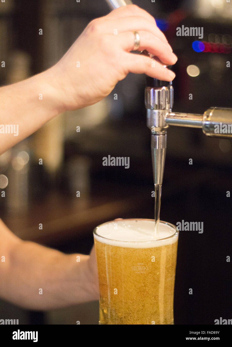 Lager draft beer pump and barman pulling pint of beer into glass in